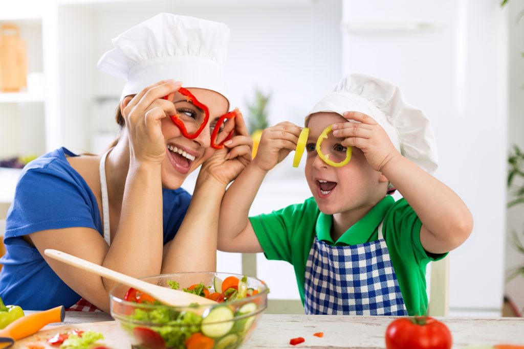 Happy family playing with vegetables in kitchen at home